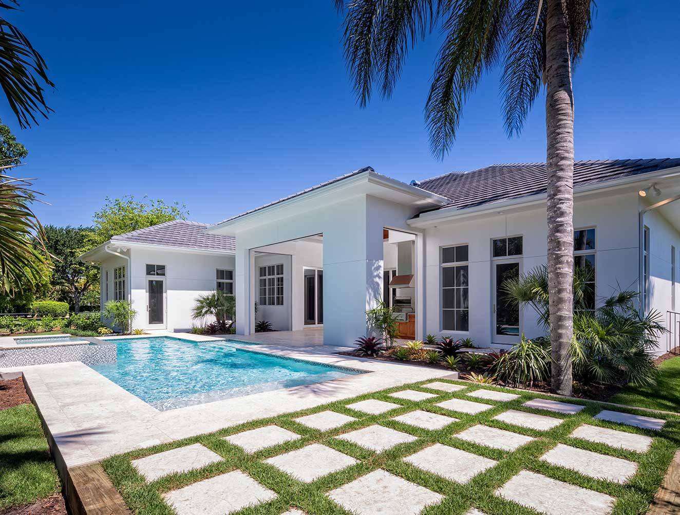Backyard oasis of traditional Florida style Naples custom home with pool and decorative stone pavers