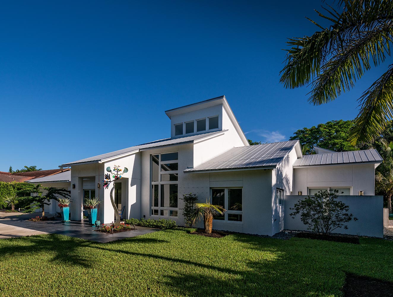 Modern Naples custom home with abstract art installation, landscaping and custom windows